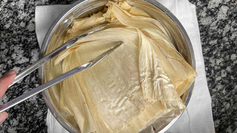 Corn husks soaking in water in bowl