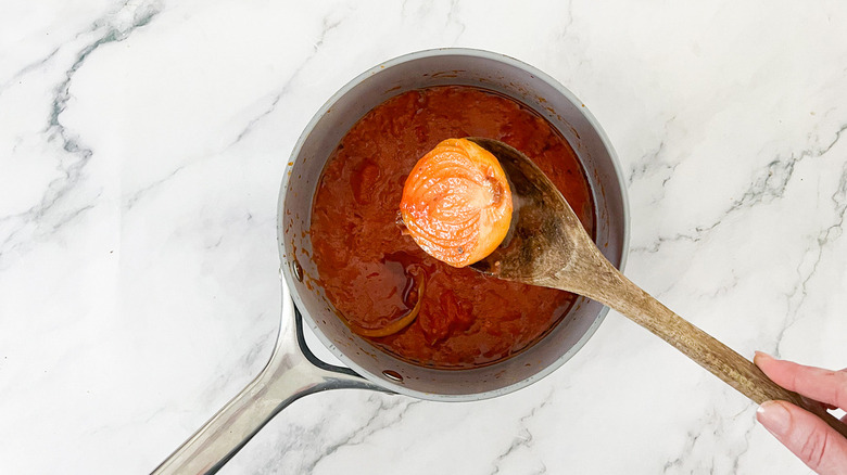 spoon lifting onion from tomatoes