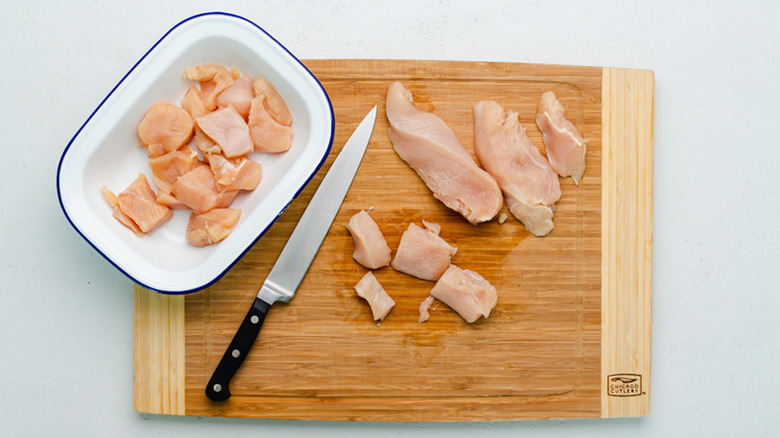 chicken bites in a blue and white bowl and on a cutting board alongside a knife