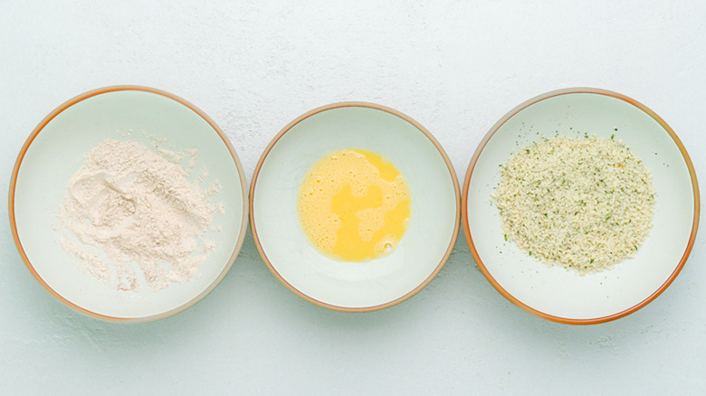 three bowls of flour mixture, egg mixture, and seasonings