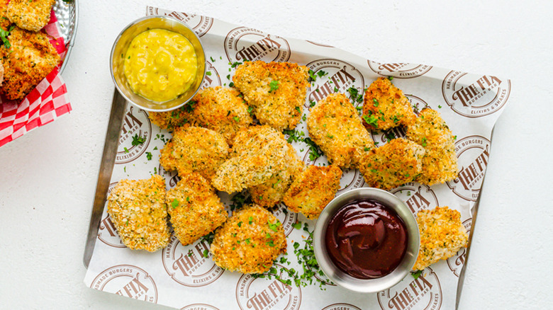 tray of breaded air fryer chicken nuggets with dipping sauces in two metal containers