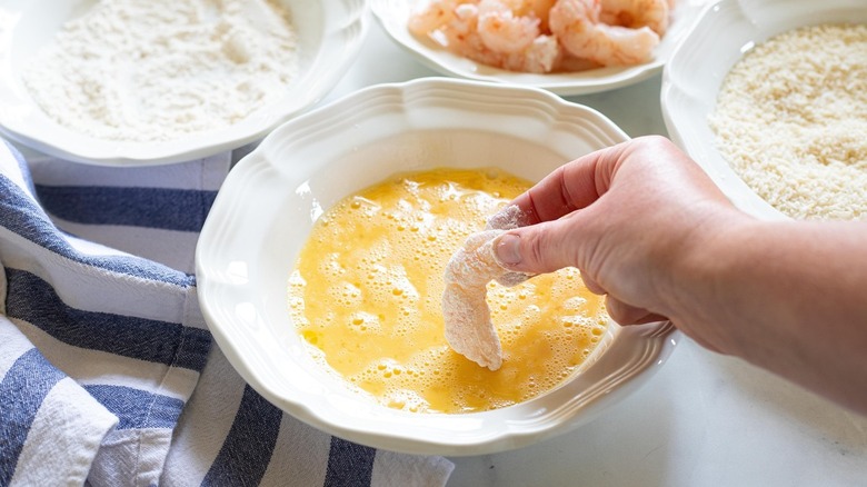 dunking shrimp into beaten eggs