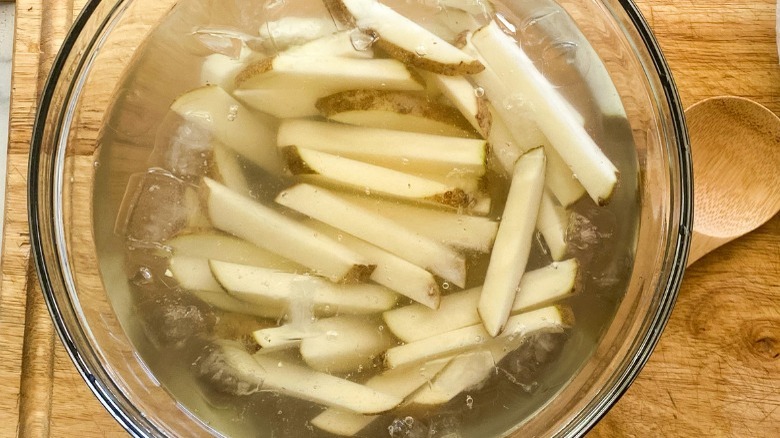 Julienned potatoes soaking in a bowl of ice water before being fried in the air fryer