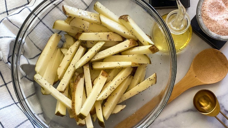 Seasoned julienned potatoes in a bowl, waiting to be fried in air fryer