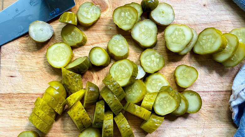 sliced pickles on top of a wooden surface with a knife