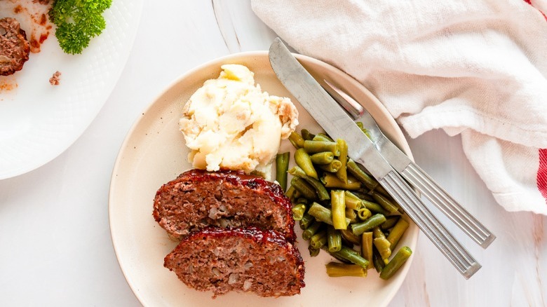 meatloaf on plate with mashed potatoes and green beans