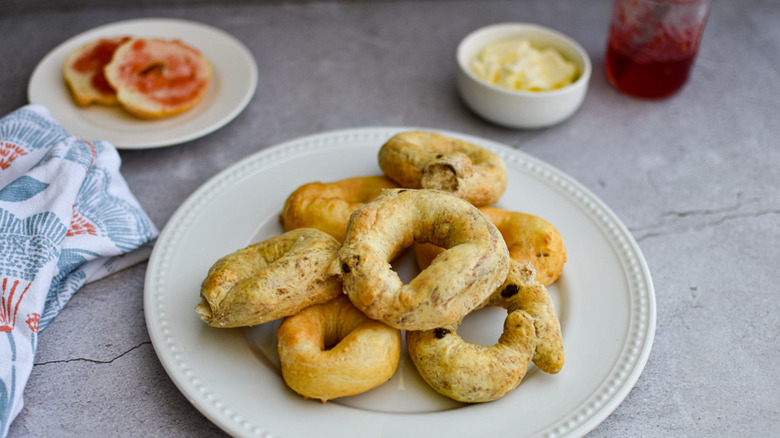 mini air fryer bagels on a white plate with a white bowl of butter and a jar of jelly