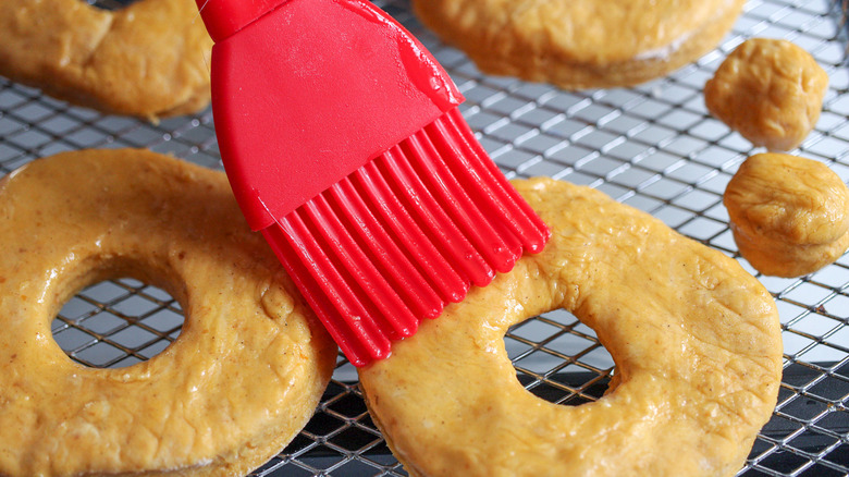 brushing pumpkin donuts with oil 