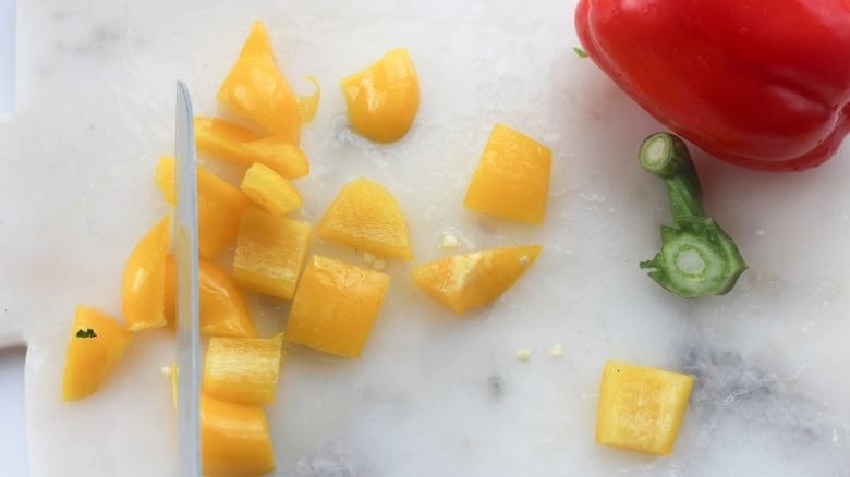 roughly chopped yellow bell pepper next to whole red bell pepper