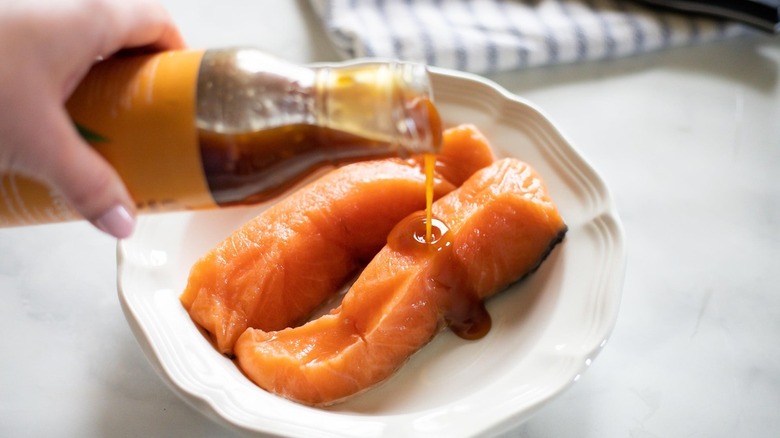 pouring teriyaki sauce on salmon