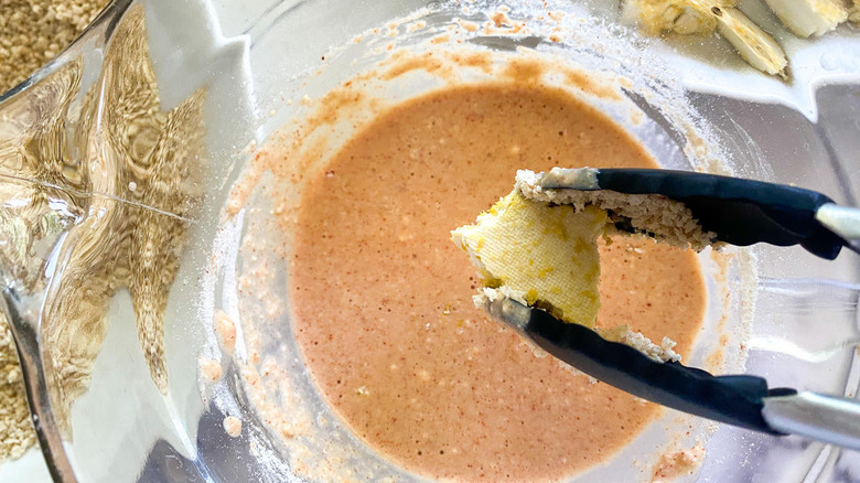 tongs dunking tofu in batter