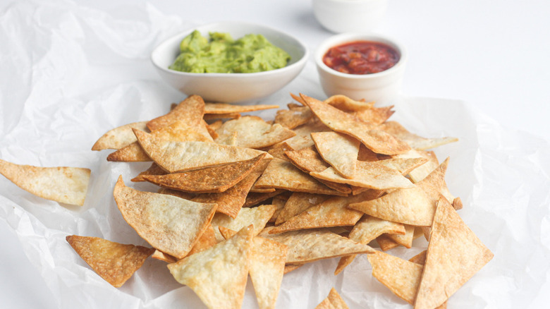 Finished tortilla chips on plate with guac and salsa