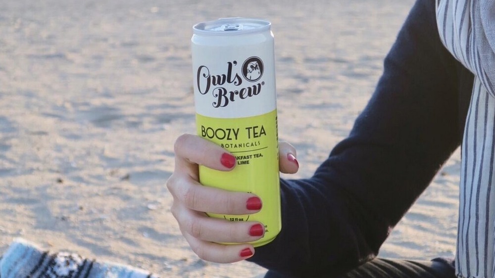 A woman holding an Owl's Brew can