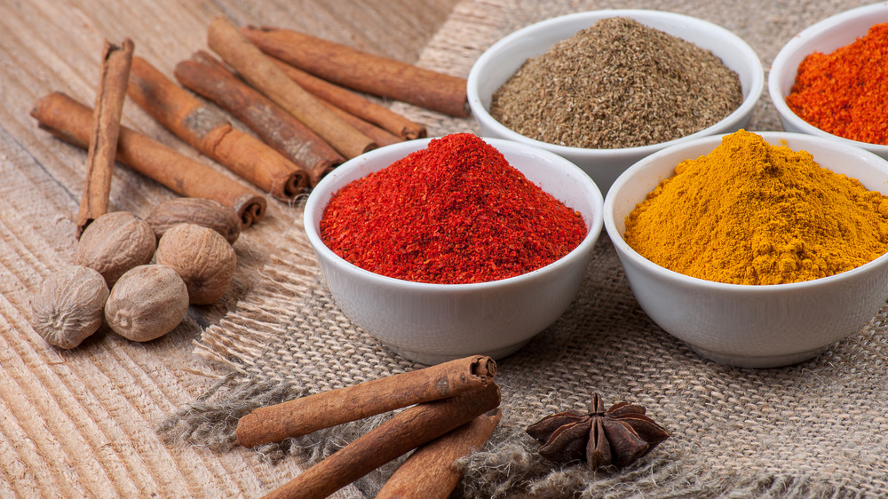 A variety of spices in bowls with whole spices