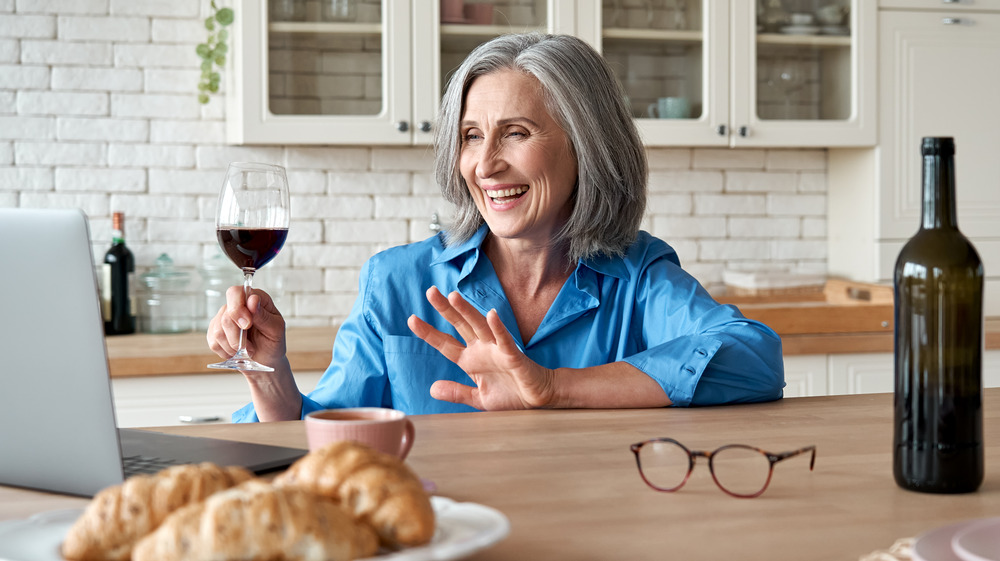 Woman drinking wine while using computer