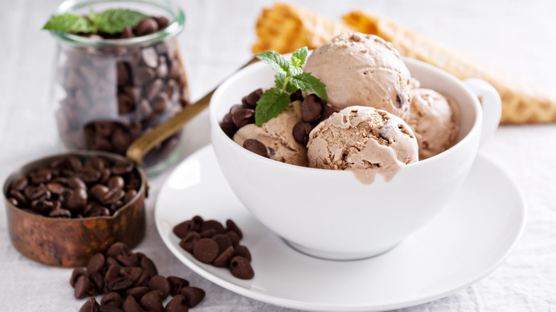 Coffee ice cream in bowl on table next to coffee beans