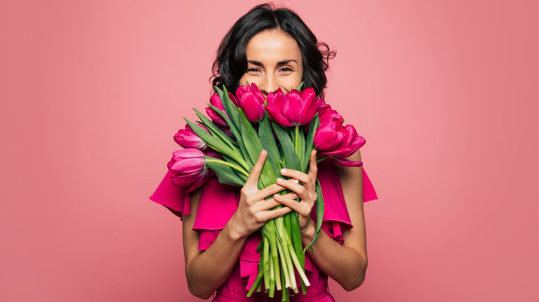 Woman smiling behind tulip bouquet