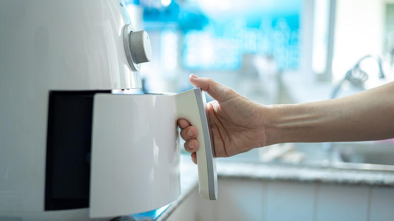 Person opening white air fryer