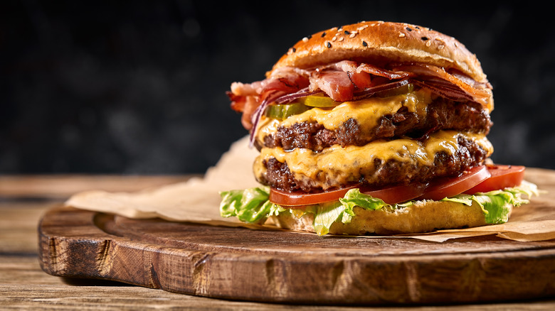 Double decker cheese burger setting on cutting board