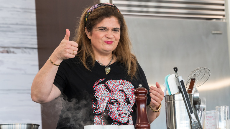 Alex Guarnaschelli in a black t-shirt giving thumbs up sign in a kitchen