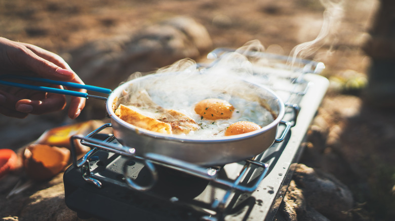 Person cooking eggs in a metal pan