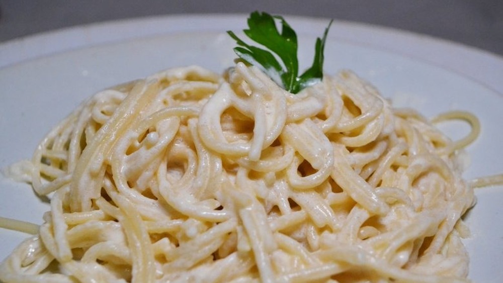 Alfredo pasta on white plate with parsley