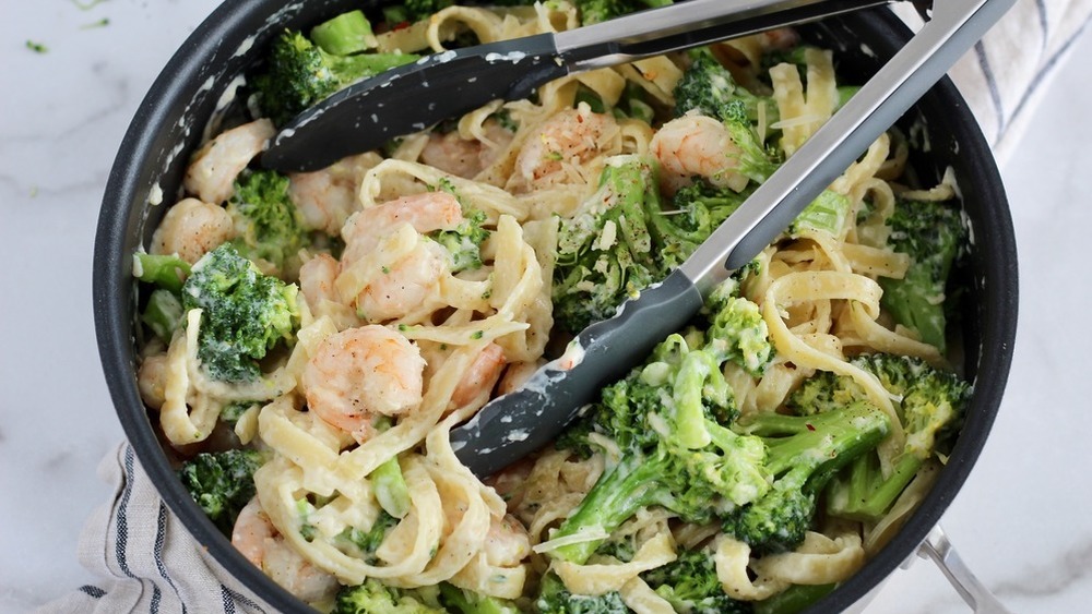 Shrimp Alfredo in a black pot with tongs