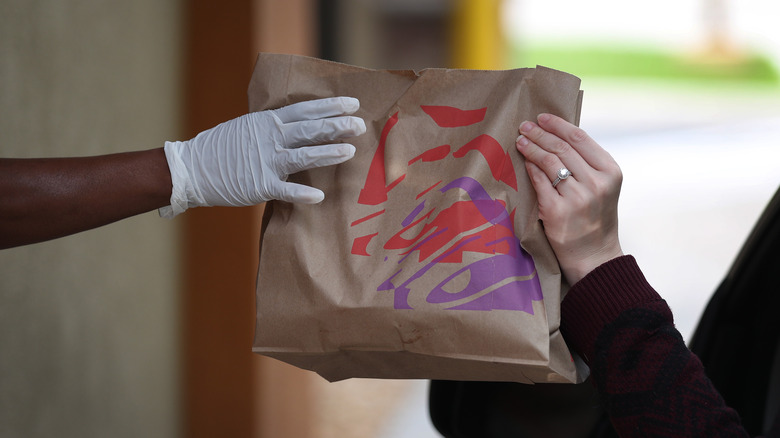 Taco Bell employee handing order to drive thru customer