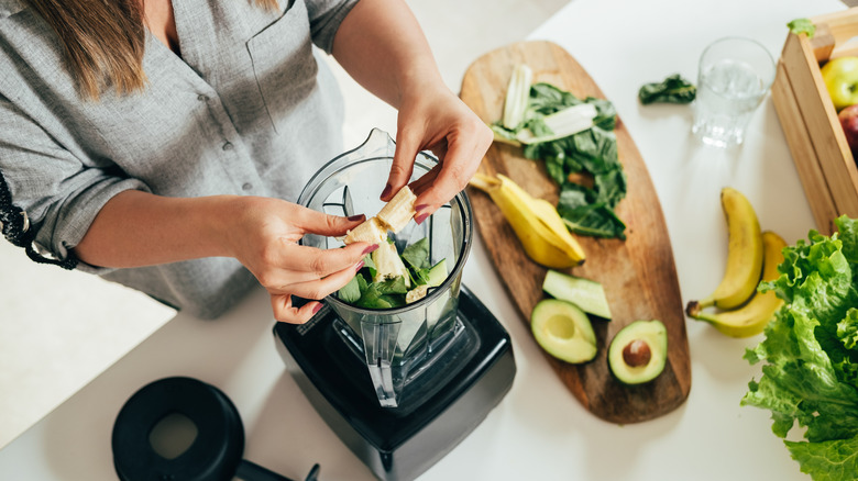 Woman putting ingredients in blender