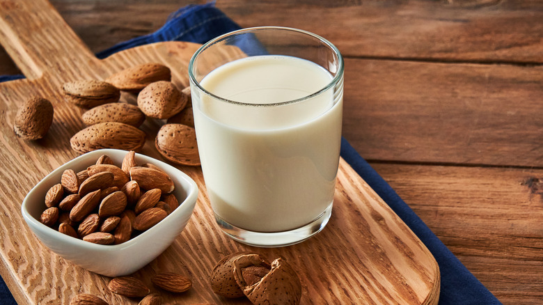 Glass of almond milk and almonds on a wooden board