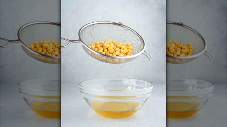 strainer of chickpeas over bowl of aquafaba