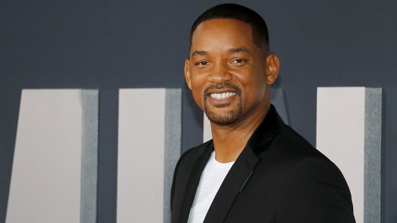 Will Smith with wide smile wearing black suit jacket