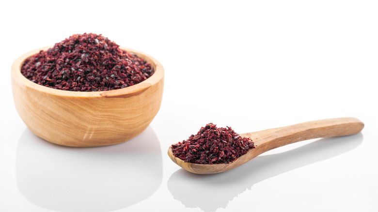 Sumac in wooden bowl and on wooden spoon