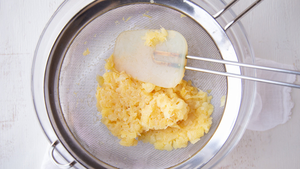 Crushed pineapple in a strainer for ambrosia recipe