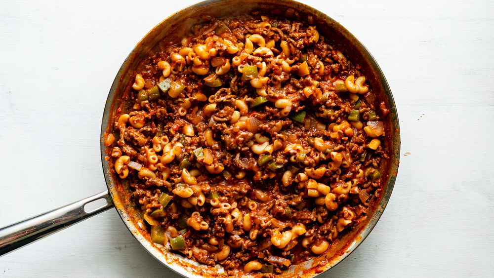 adding in tomatoes to American goulash