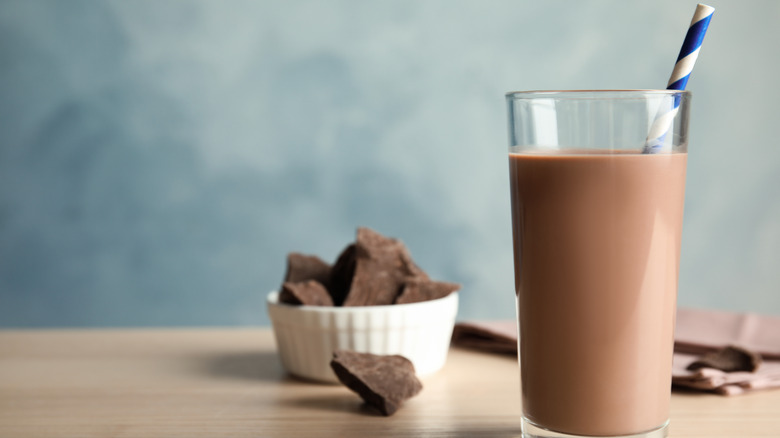 Chocolate milk with straw next to bowl of chocolate