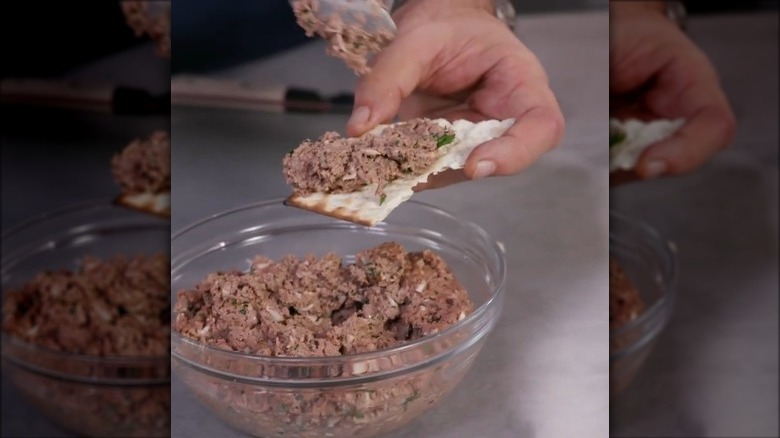 Chopped Chicken liver in a clear bowl with a cracker