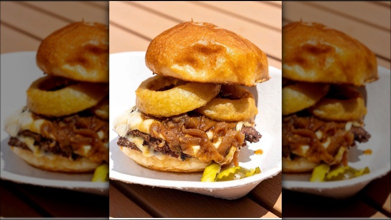 cheeseburger with onion rings and caramelized onions on a white plate