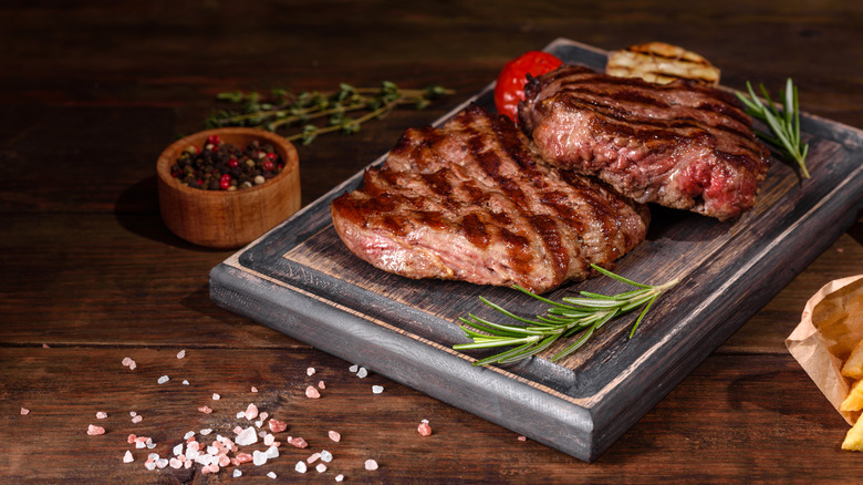 cooked steak resting on cutting board