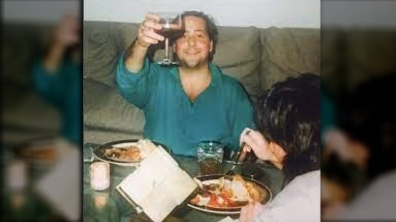 Young Andrew Zimmern raising a glass of wine in toast