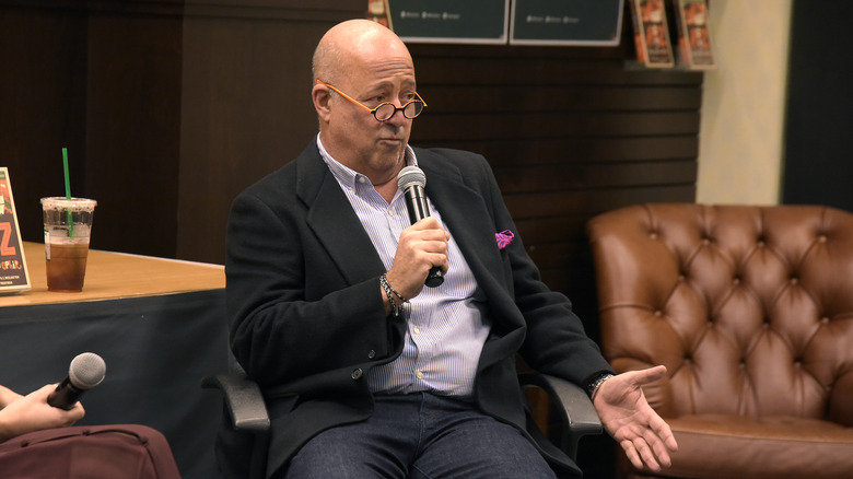 Andrew Zimmern holding a mic and speaking