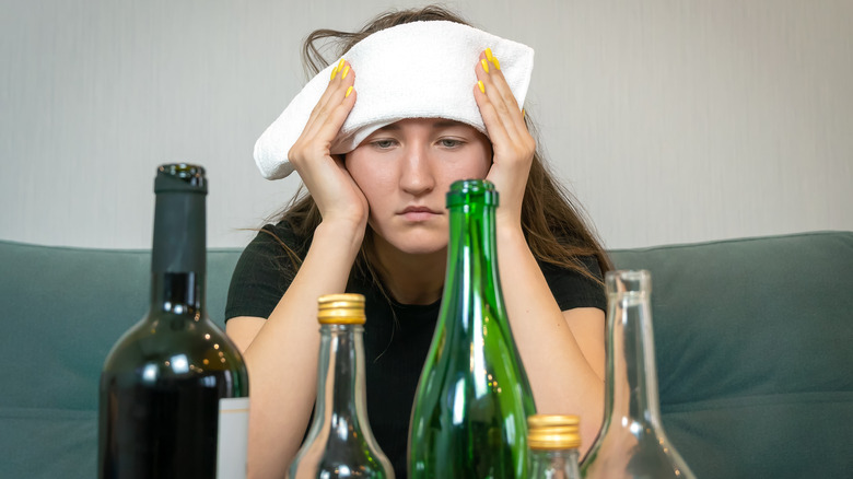 hungover woman pressing towel against forehead