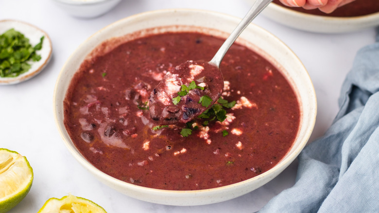 Spooning purple black bean soup out of bowl