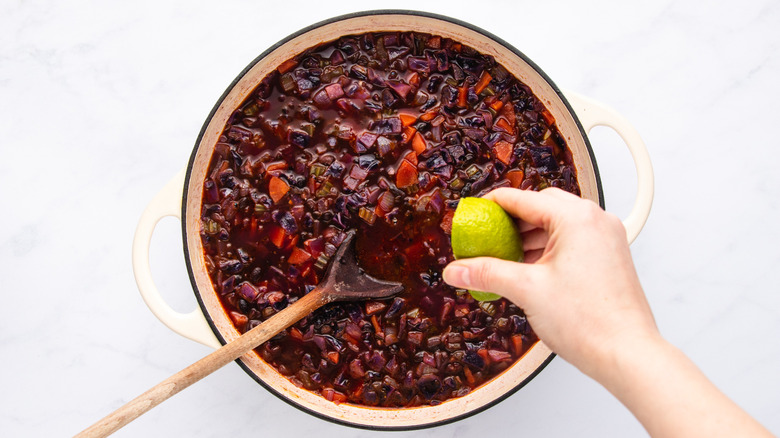 Squeezing lime into pot of red cabbage black bean soup