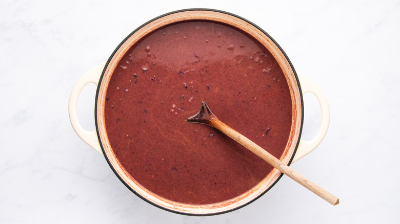 Purple black bean soup in pot with wooden spoon