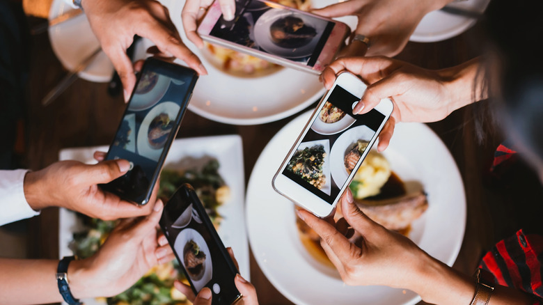 four people taking food photos