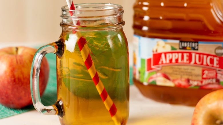 A jar of apple juice with a straw, with a Langers bottle behind.