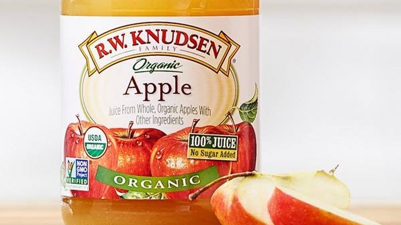 A bottle of R. W. Knudsen apple juice next to apple slices.