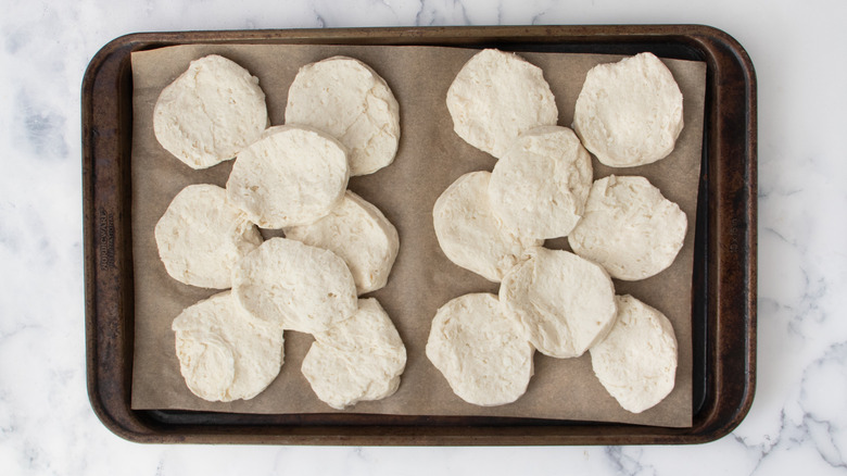 Canned biscuits split in half on a baking sheet