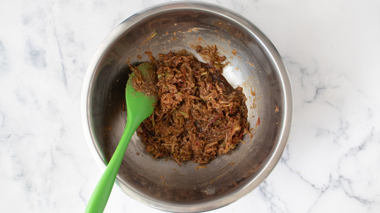 Grated apples with sugar, spices, and butter in bowl